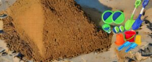 Ein Sandhaufen mit einer Schaufel und anderen Strandspielzeug-Artikeln.